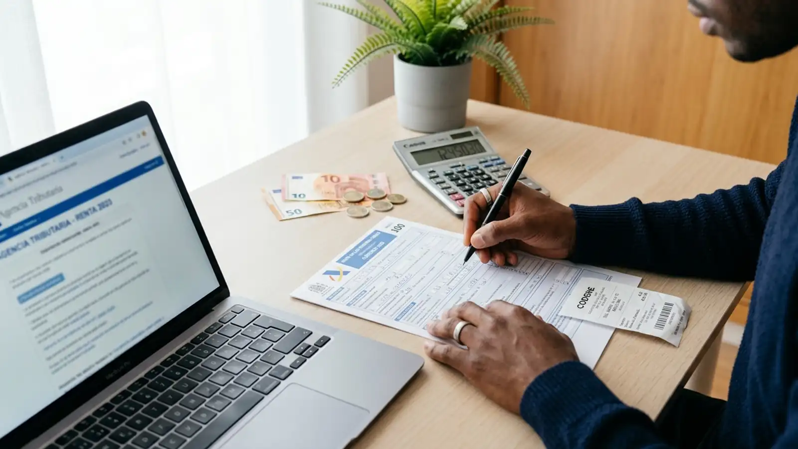 Persona rellenando la declaración de la Renta con calculadora, documentos fiscales y ordenador portátil